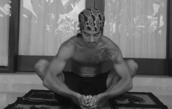 Ruwan in a seated stretch on a practice mat